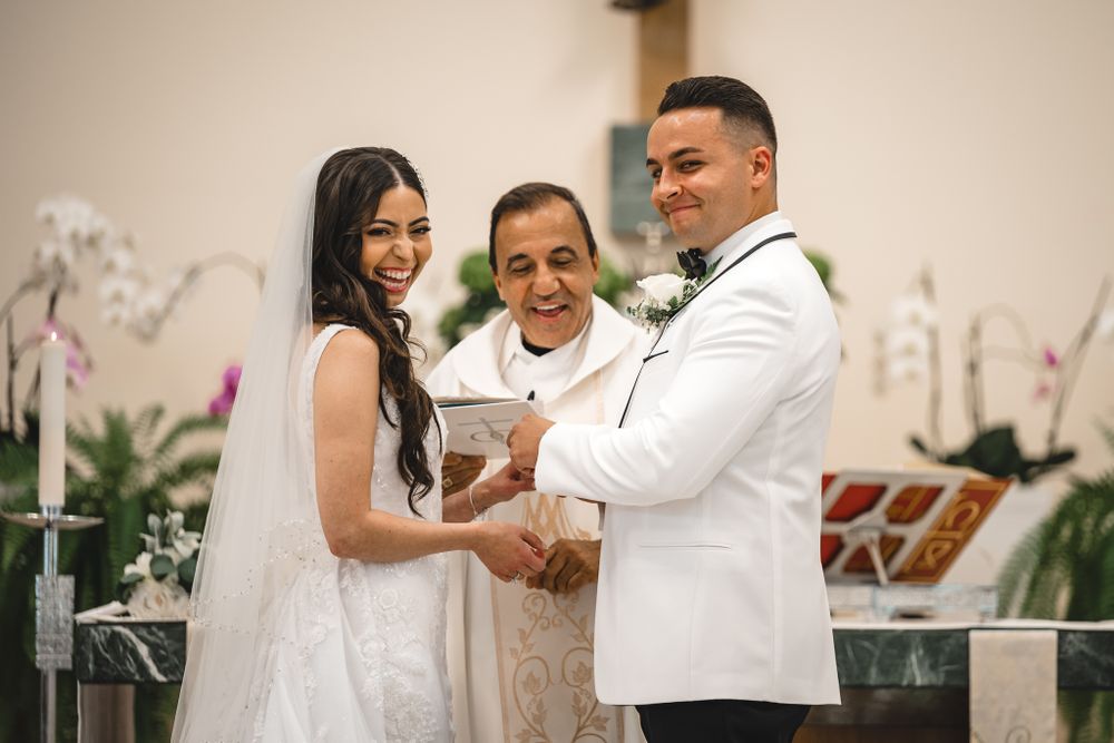 A couple exchanges vows during an intimate wedding ceremony with an officiant in an elegant indoor setting.