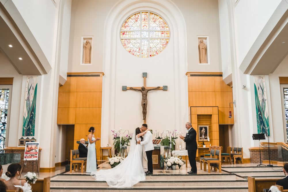 A wedding ceremony in a bright church sanctuary with stained glass windows and wooden pews.