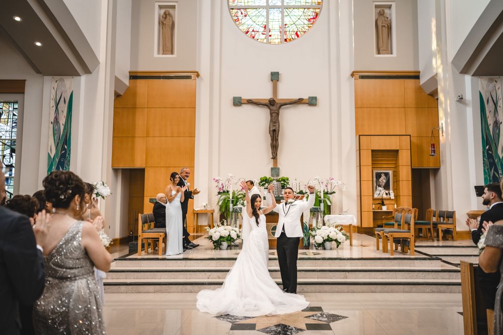 A joyful recessional down the church aisle with guests capturing photos on their phones.