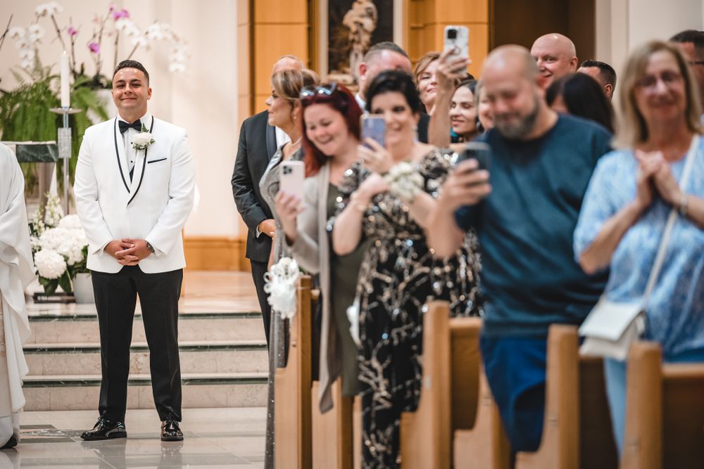 Wedding guests seated in church pews watching ceremony proceedings.