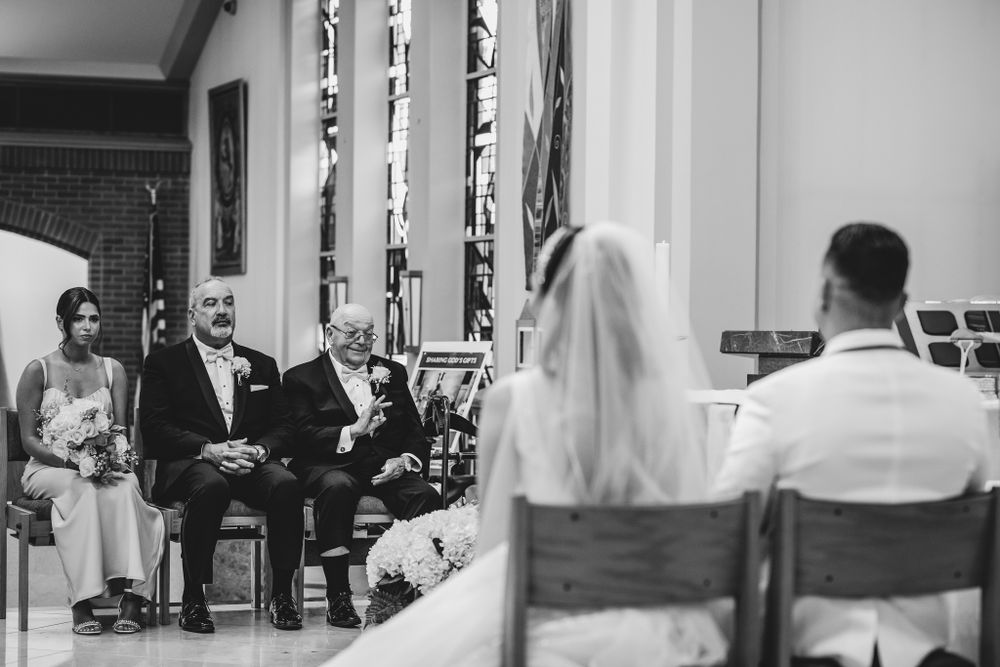 Black and white photo of wedding ceremony inside traditional church sanctuary.