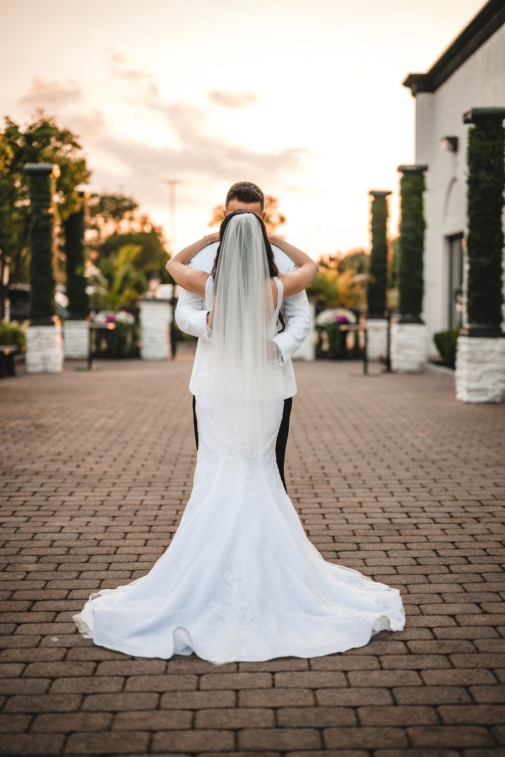 Wedding dress train laid out beautifully on brick pavers during golden hour sunset.