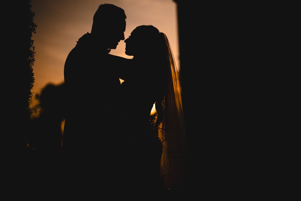 Silhouetted couple sharing an intimate moment at sunset.