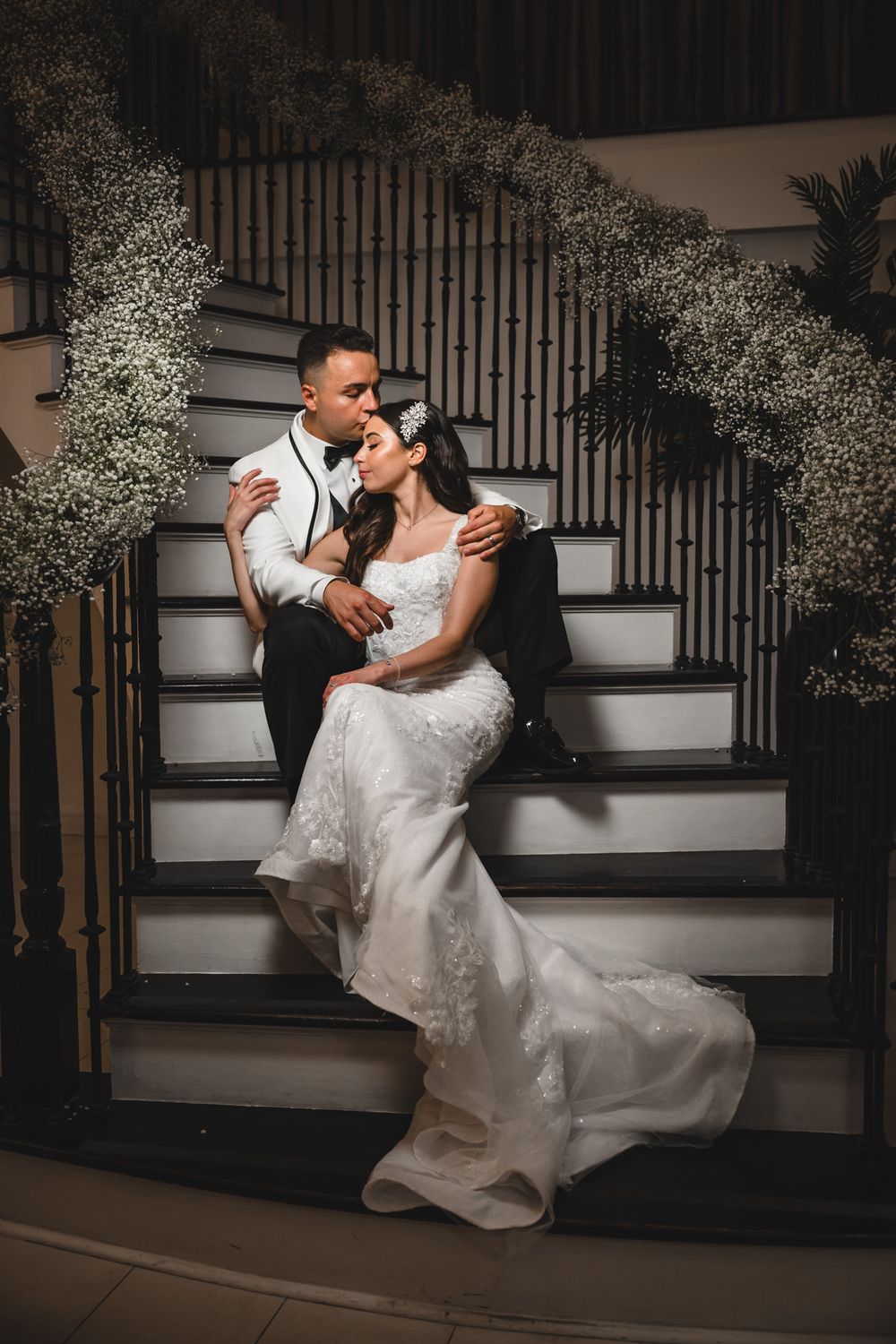 Romantic wedding photos on elegant white stairs decorated with baby's breath flowers.