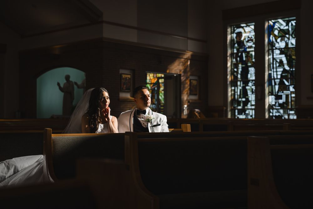 Silhouetted figures in church with dramatic lighting from stained glass windows.