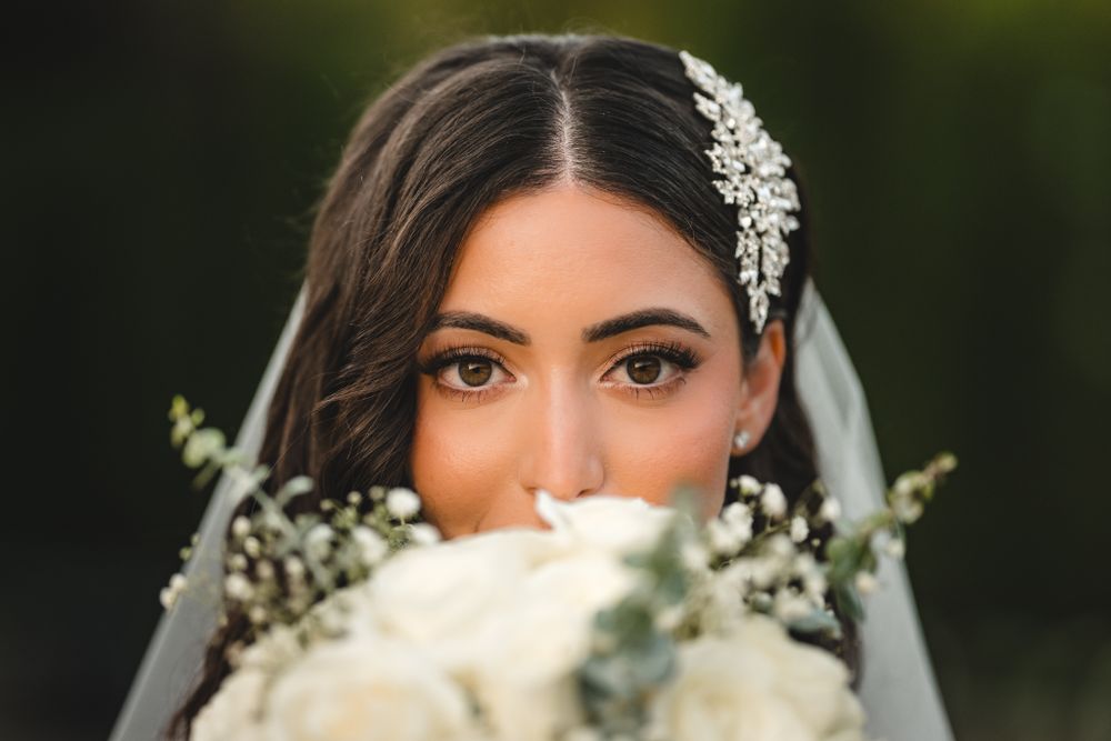 Close-up of bridal details including crystal hair accessory and white bouquet.