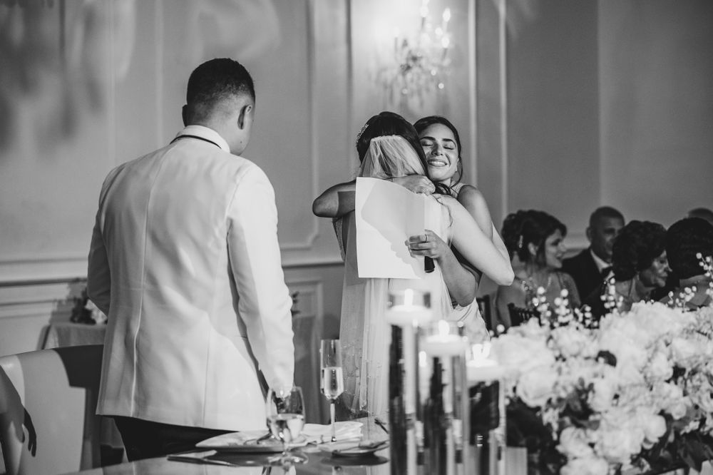 Black and white photo of wedding reception moments at decorated head table.