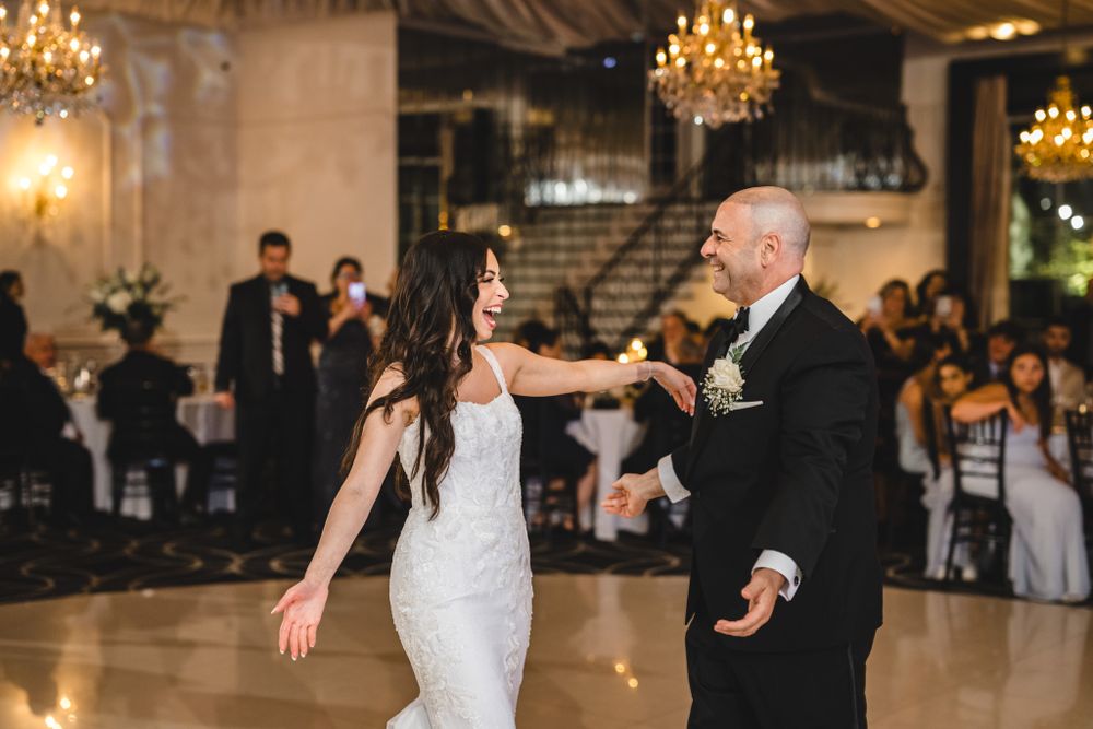 Dancing moment captured during wedding reception in elegant ballroom with chandeliers.