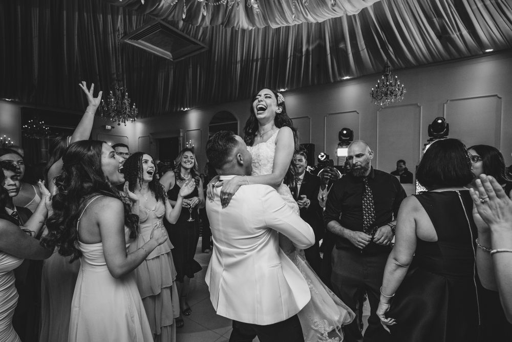 Panoramic view of wedding reception dance floor with guests celebrating under draped ceiling.