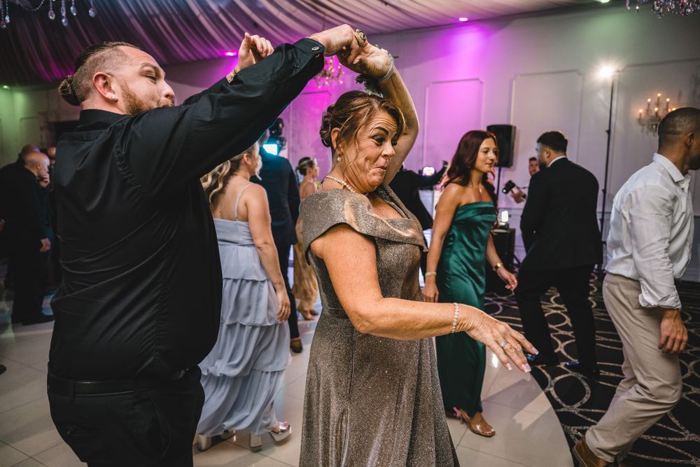 Dynamic dance floor scene at wedding reception with colorful lighting and elegant decor.