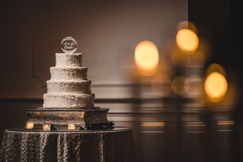 White wedding cake with textured frosting displayed with warm bokeh lighting.