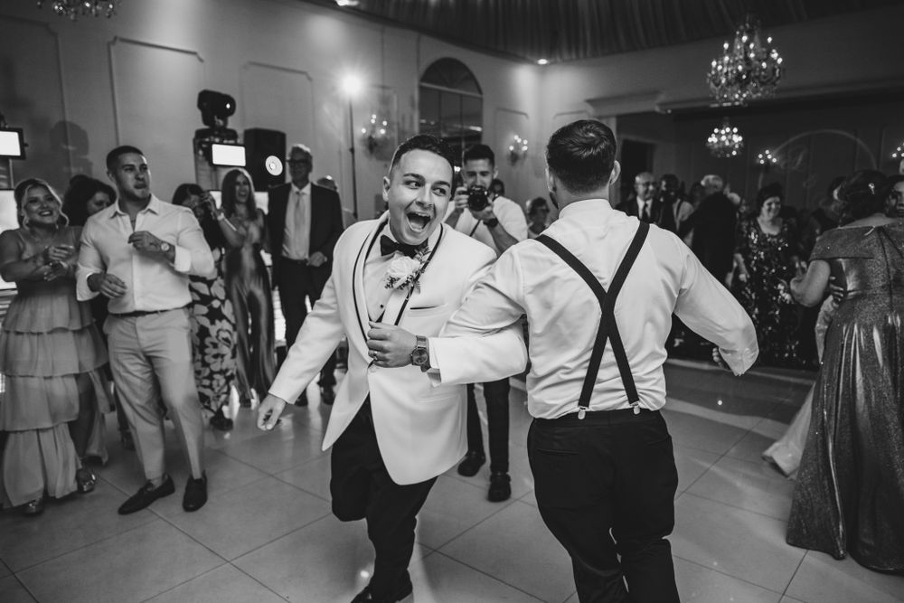 Wide angle view of wedding guests dancing and celebrating in a spacious reception hall.
