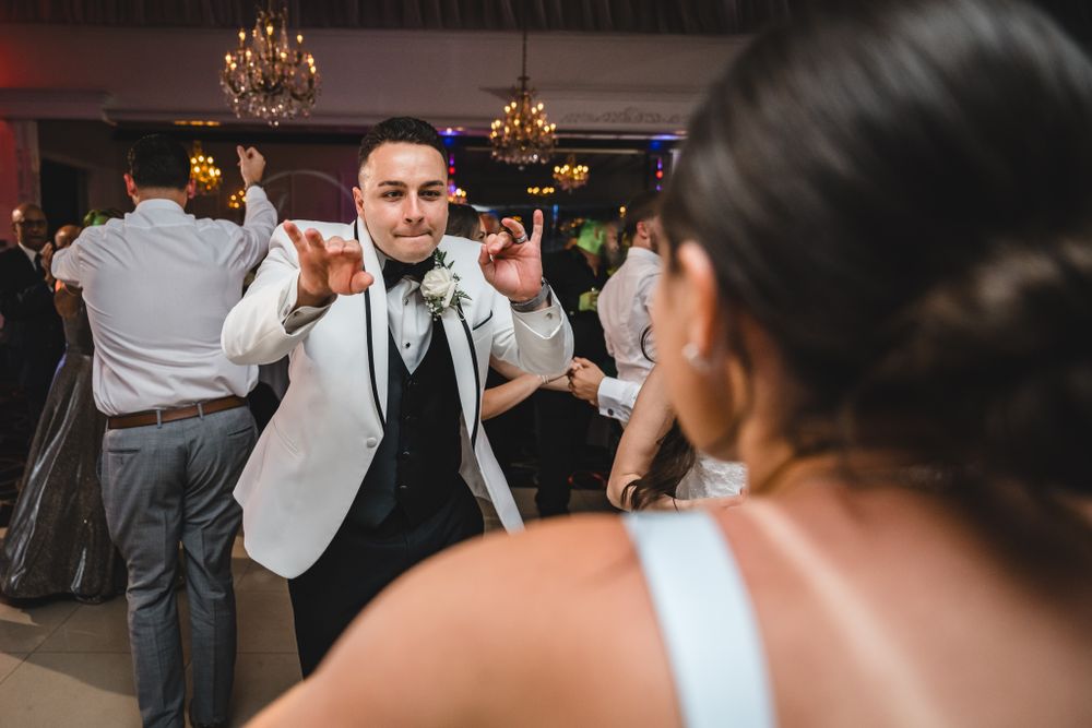 Wedding reception dance floor filled with celebrating guests under dramatic lighting.