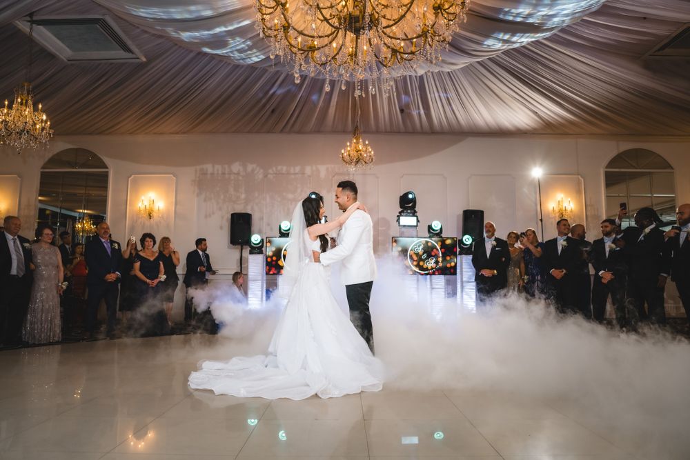 First dance in an elegant ballroom with dramatic lighting and fog effects on the dance floor.