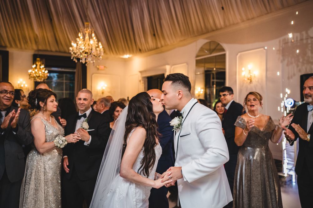 Couples dancing together during wedding reception in an elegant ballroom with crystal chandeliers.