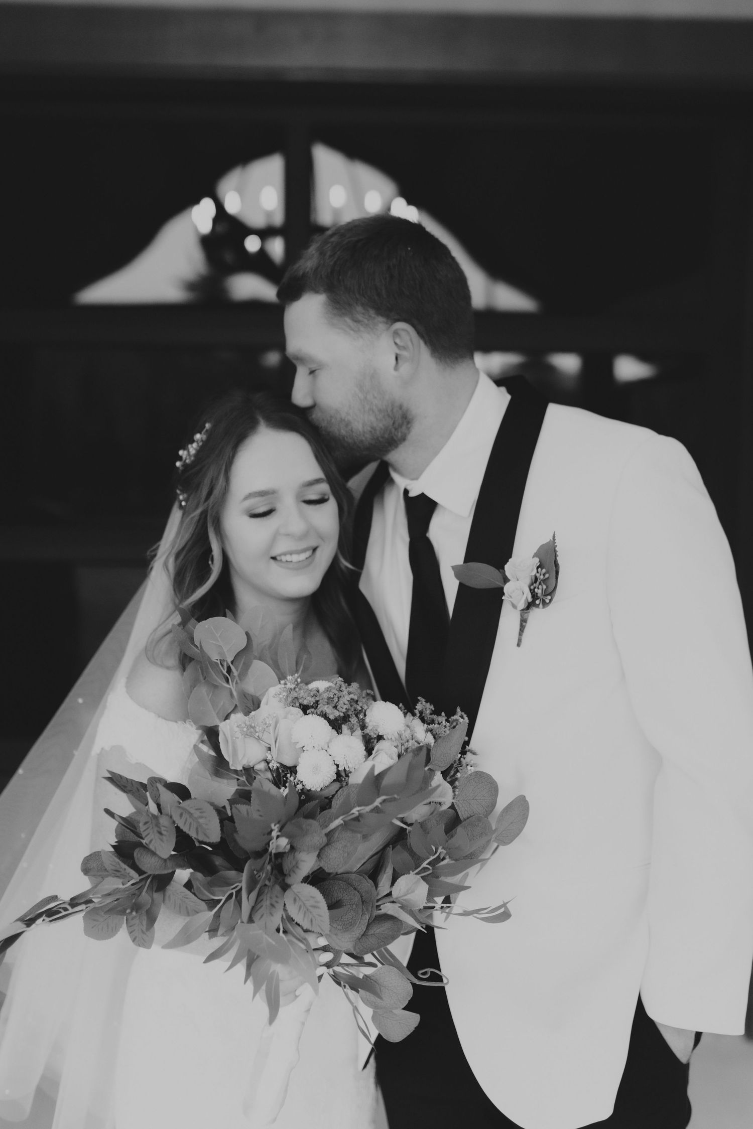 Romantic black and white wedding portrait with bride holding elegant bouquet.
