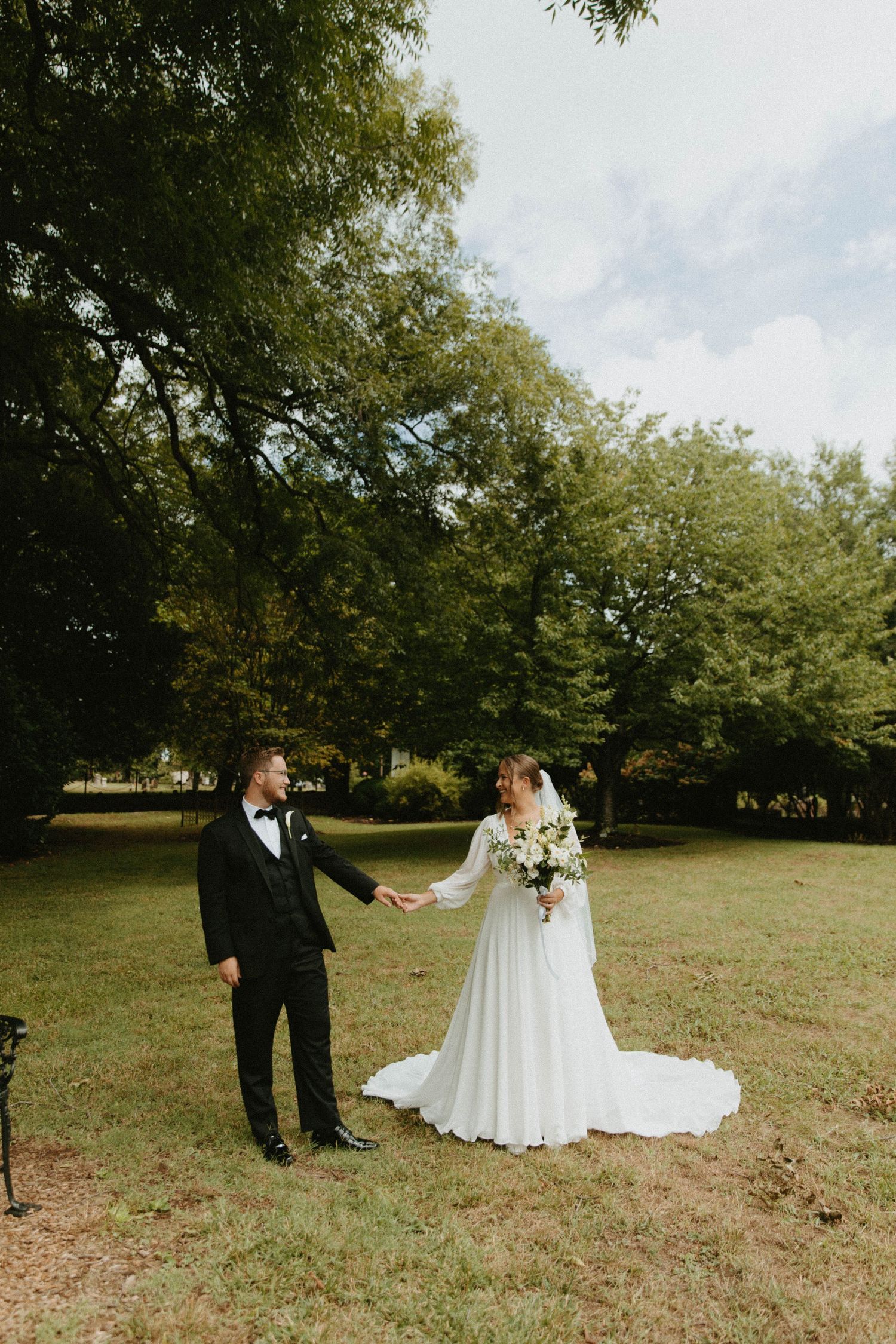Newlyweds share a tender moment in a lush garden setting with the bride in a flowing white dress.