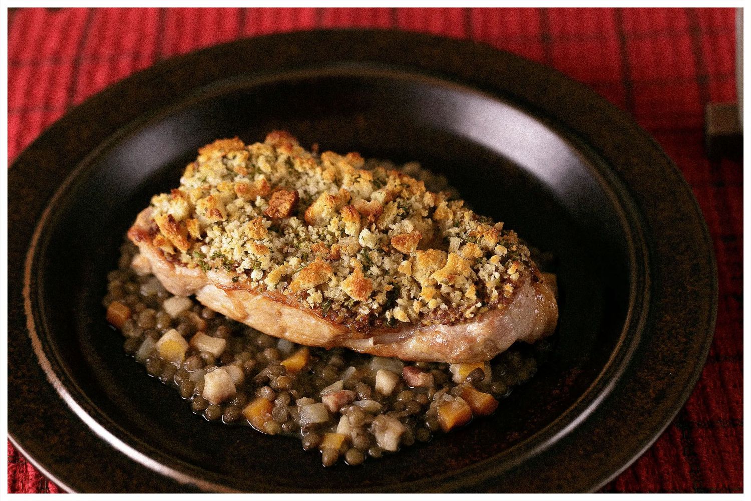 A series of black plates showing the preparation stages of a stuffed pork tenderloin with herbs and breadcrumbs.