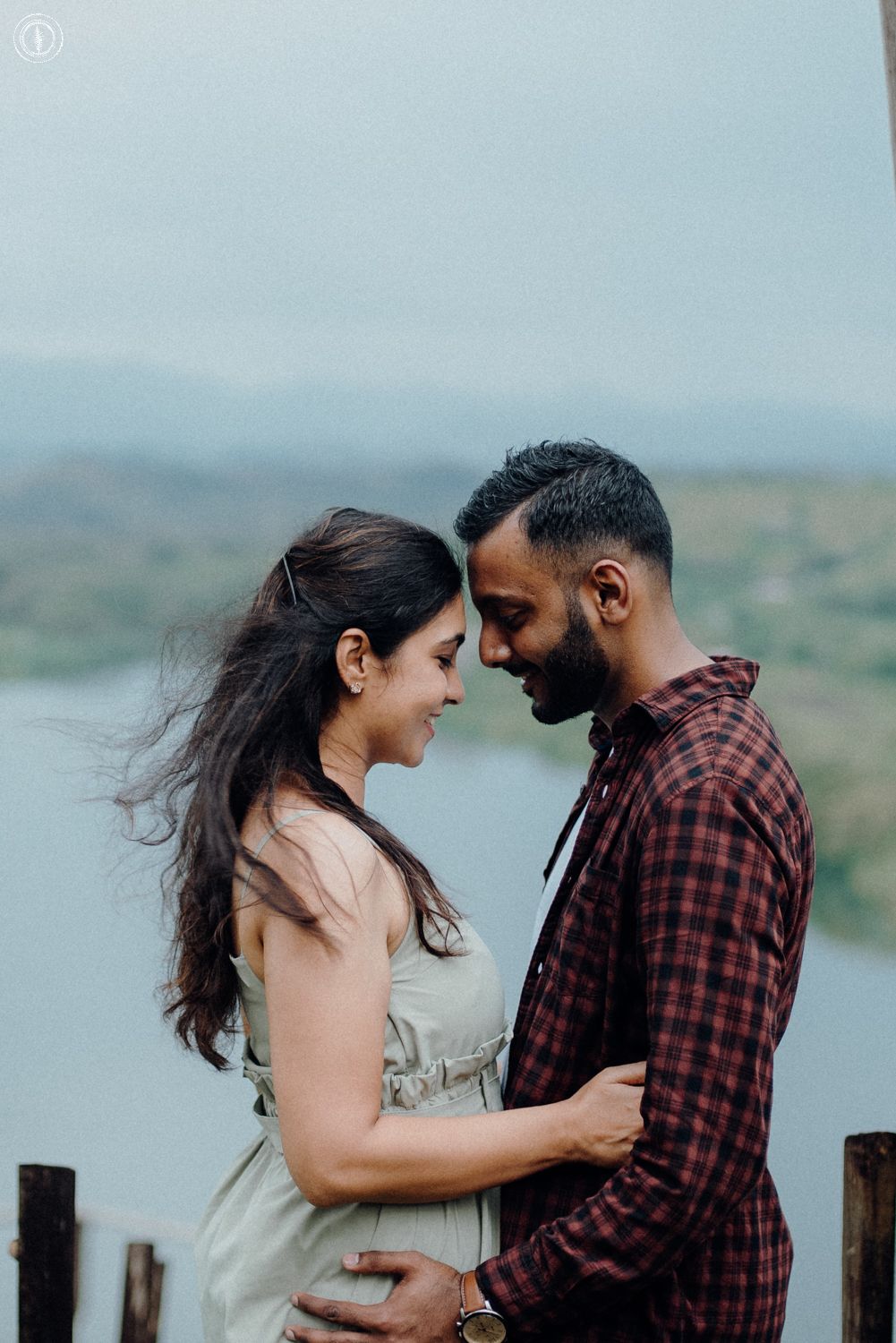 Intimate romantic moment between couple against mountain lake backdrop.