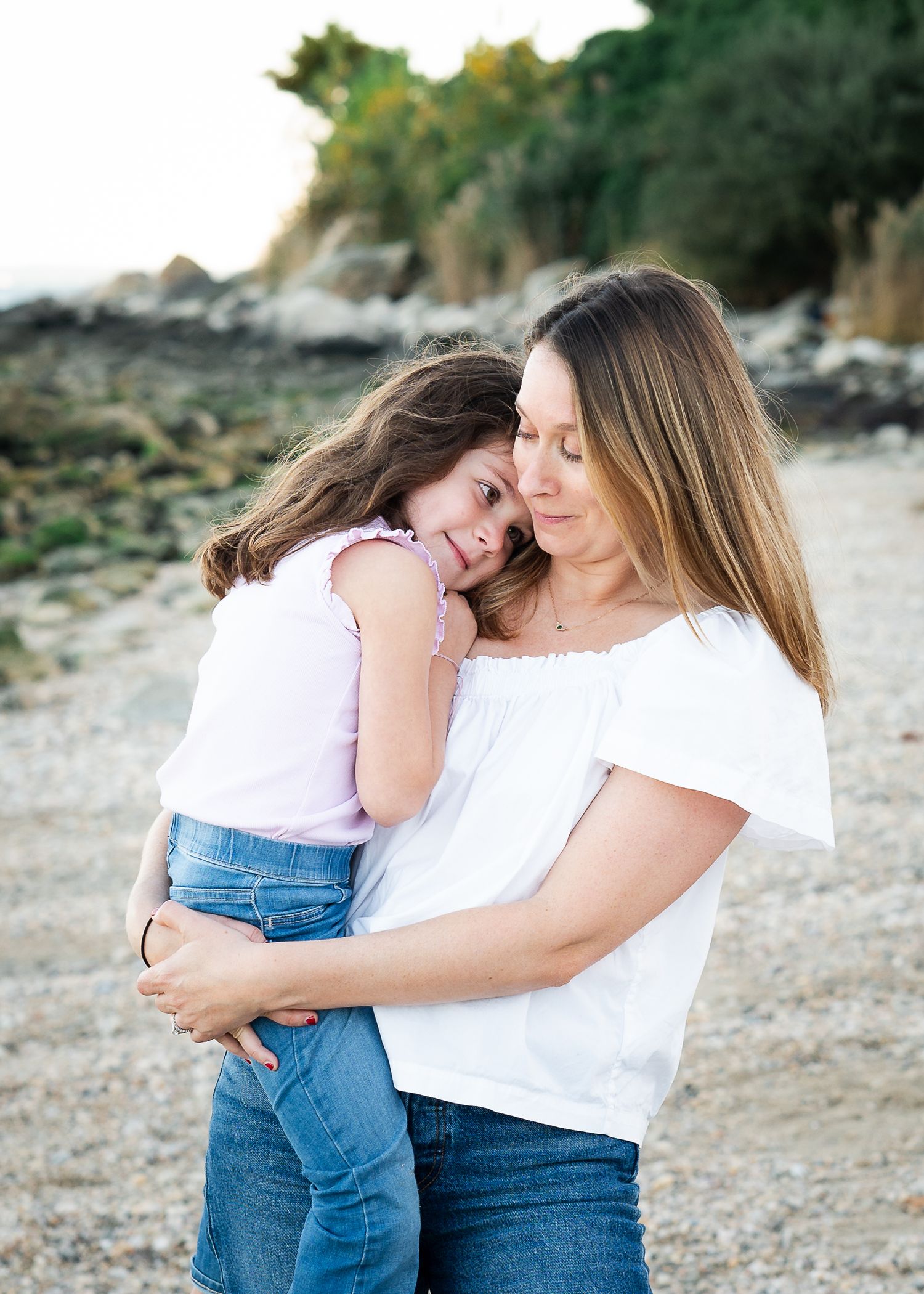 A tender moment shared between parent and child as they embrace on a rocky beach at sunset.