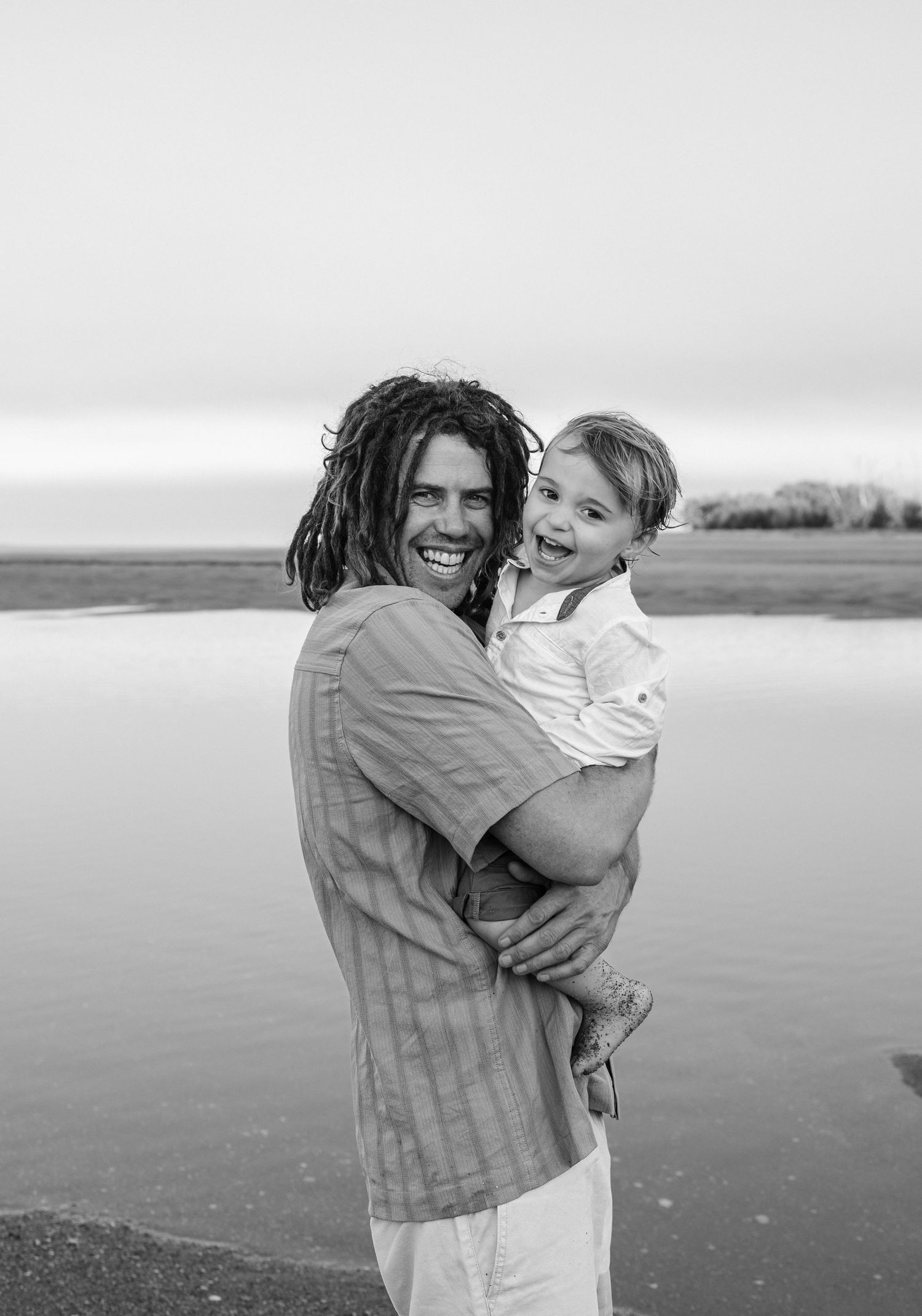 Black and white photo sequence showing playful embrace and laughter on a scenic beach.