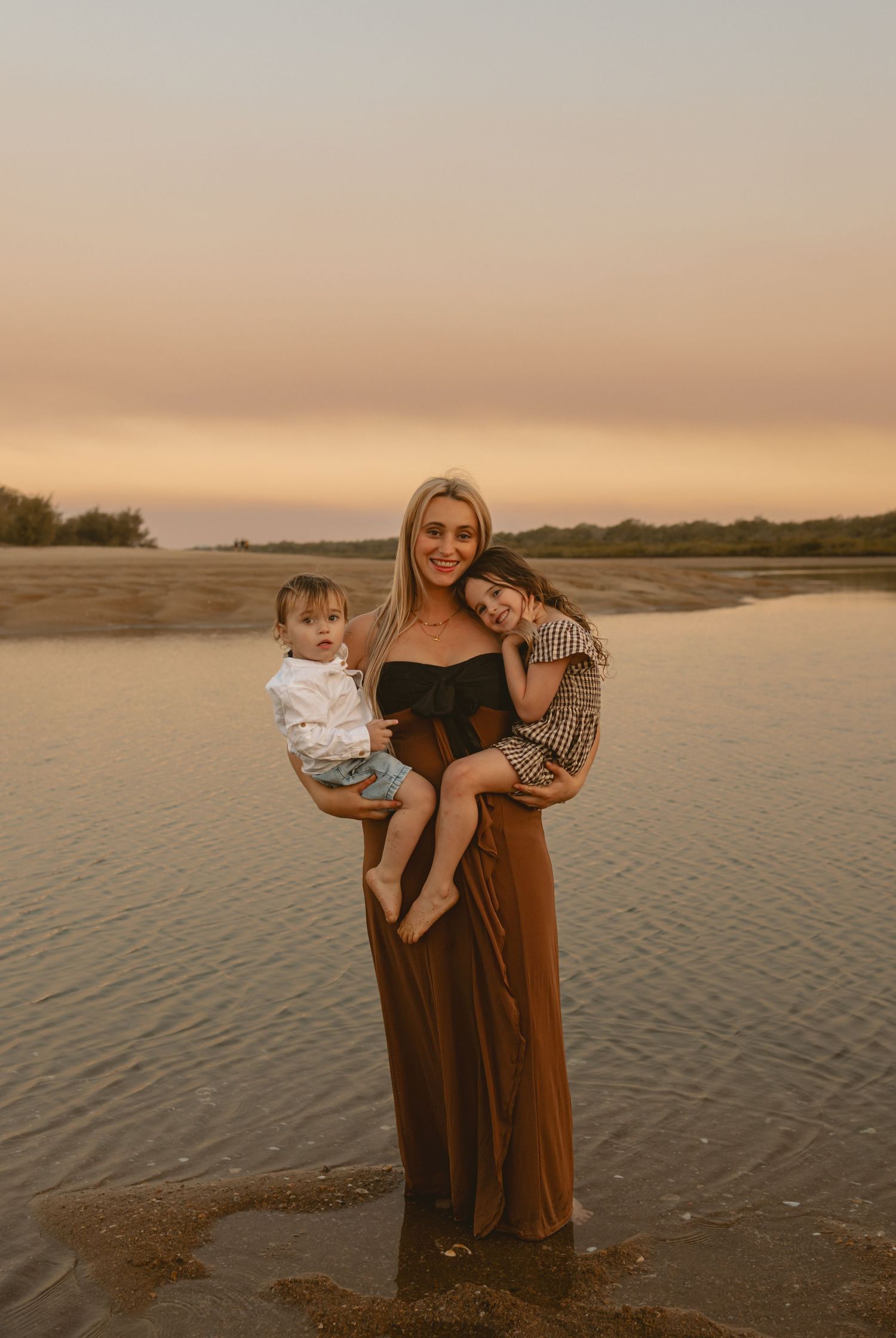 A series of sunset family portraits taken on a sandy beach with warm golden lighting and calm water in the background.