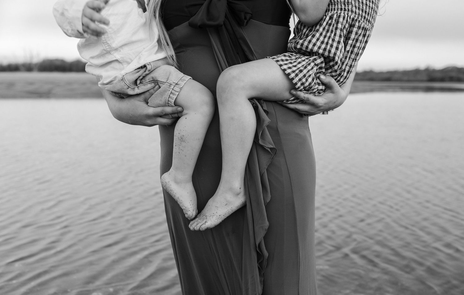 Black and white photos show a couple holding their baby at the beach during an intimate family portrait session.