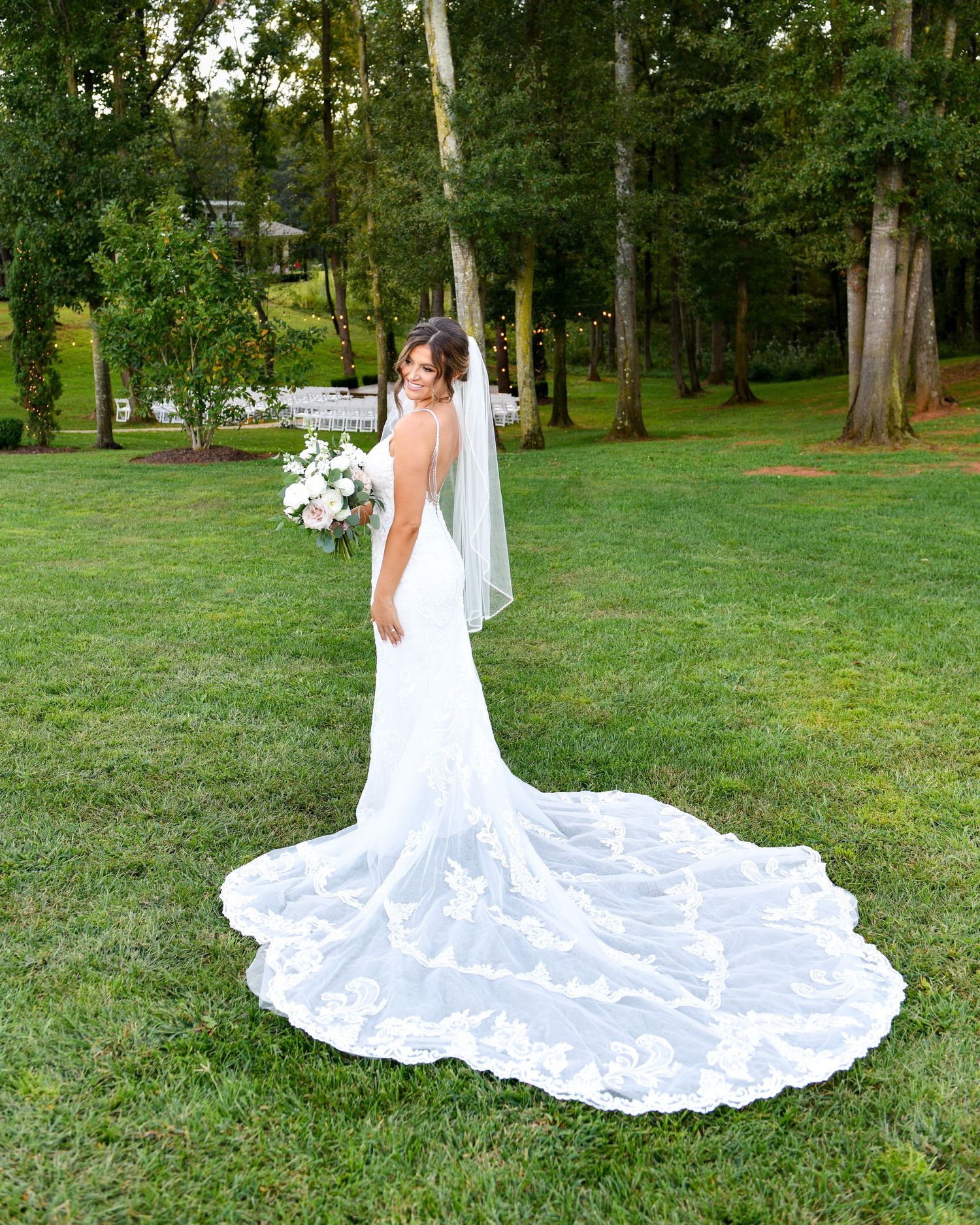 Elegant bridal portrait showing the intricate lace details of a white wedding gown with cathedral train.