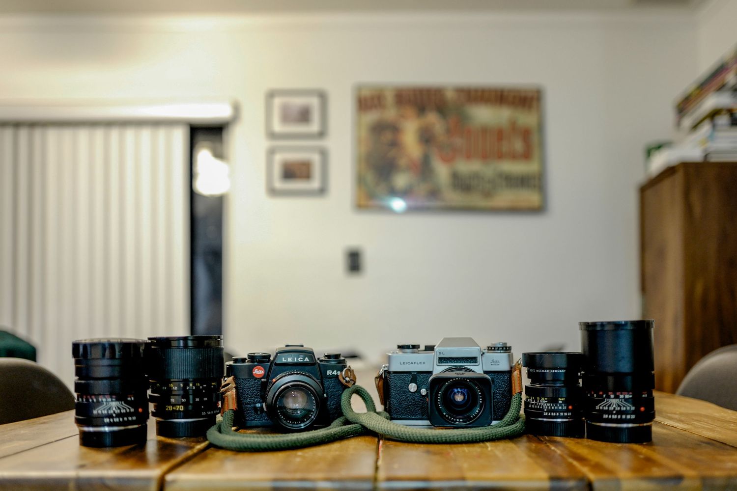 Vintage film cameras and lenses arranged on a wooden table.
