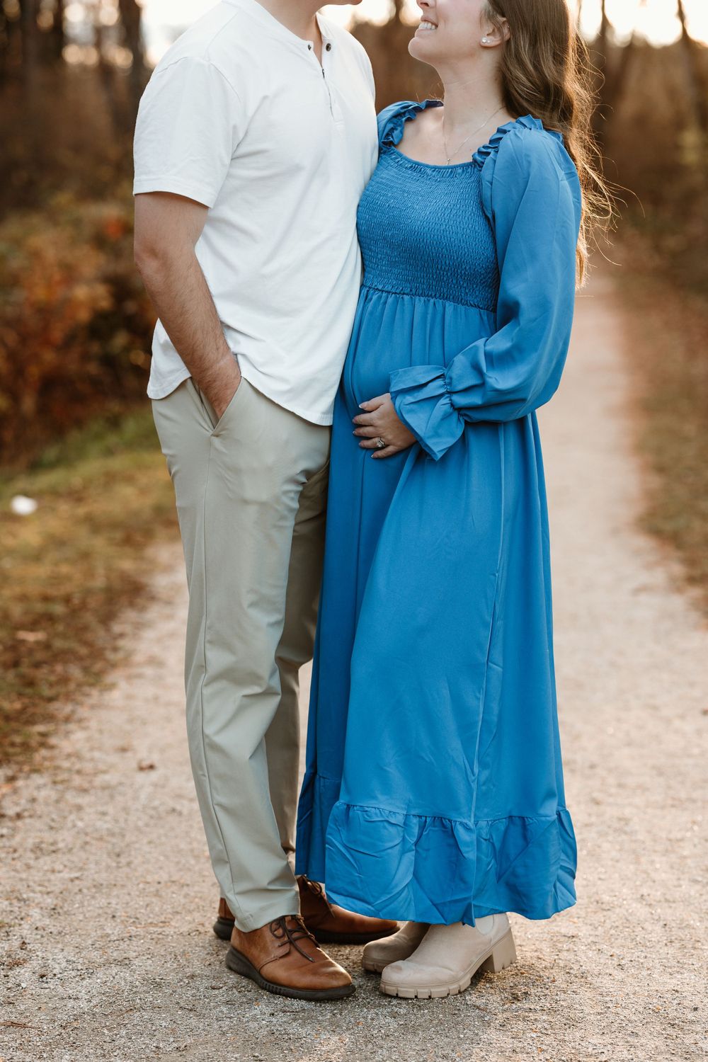 Couple in coordinated white and blue outfits sharing an intimate moment outdoors.