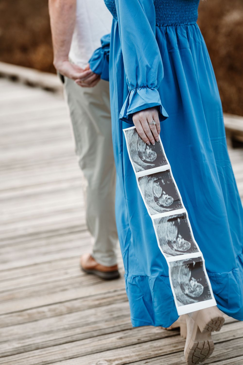 Close-up of ultrasound photos being held against a flowing blue dress.