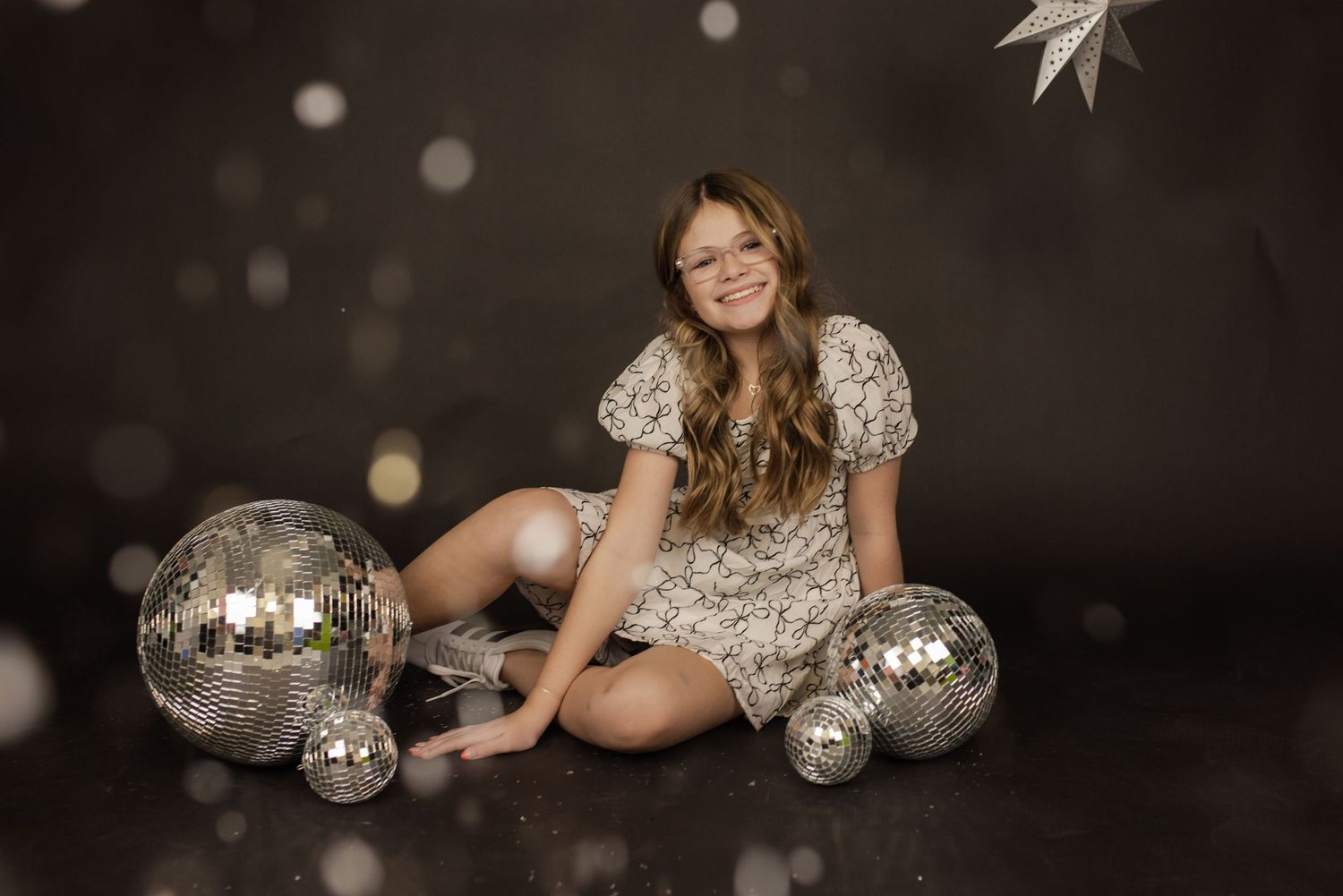 Glamour portrait session with disco balls and sparkly elements on dark background.