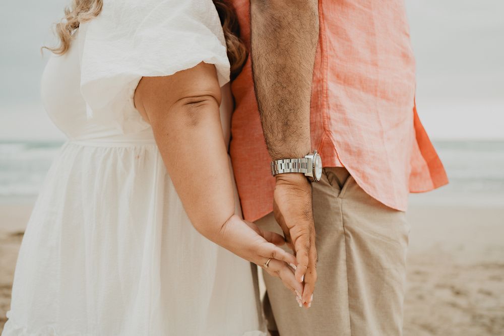 Couple from behind, holding hands, beach background