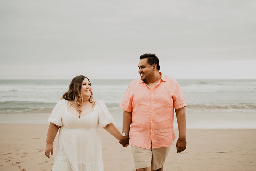 Couple looking at each other, holding hands, beach and ocean background