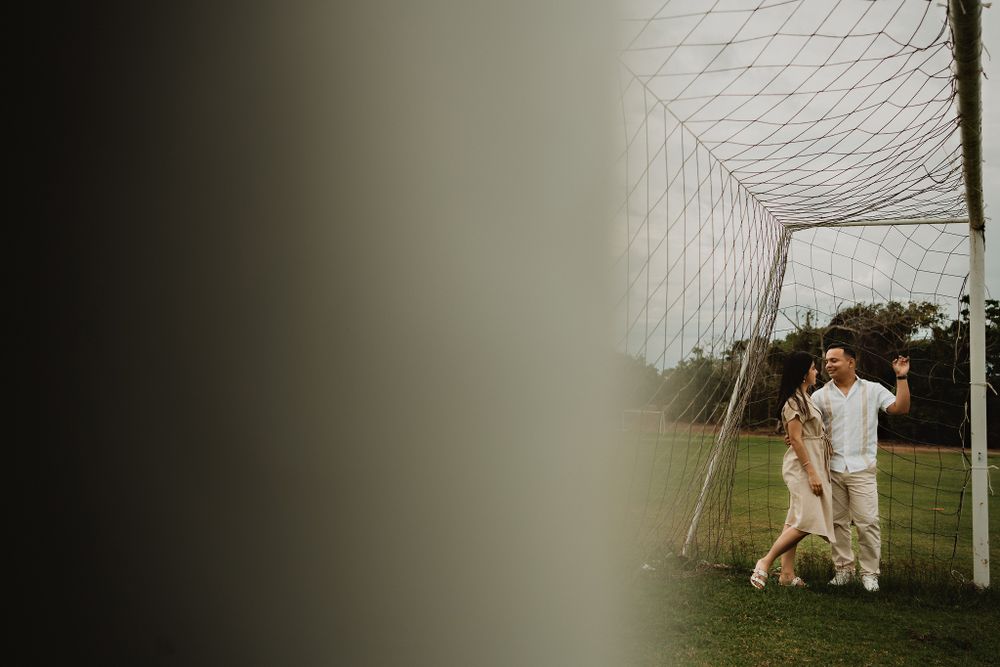 Embracing in a soccer goal, blending fun with romance at their destination wedding shoot