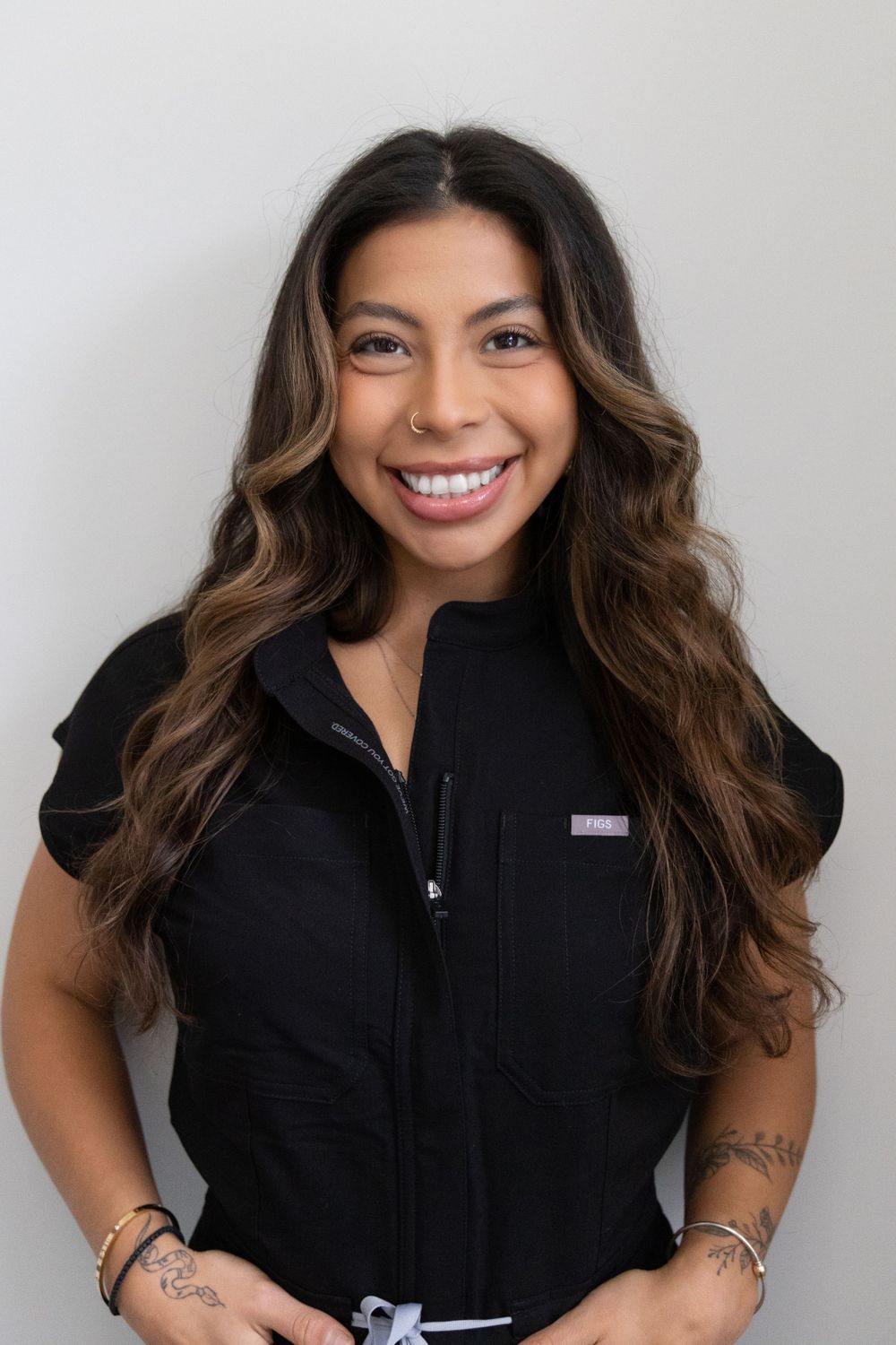 Smiling woman with long wavy hair in black scrubs uniform.