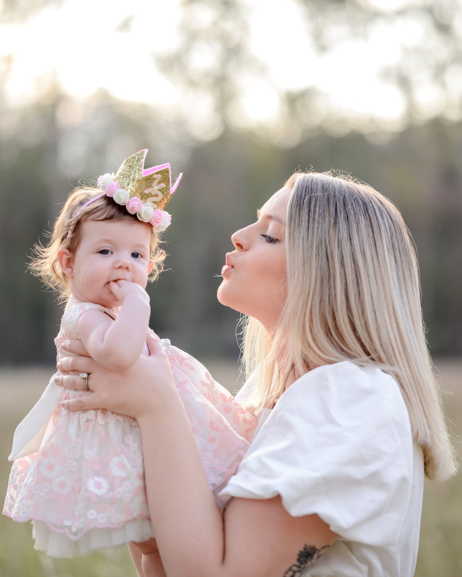 Tender moment between parent and child in pink dress outdoors.