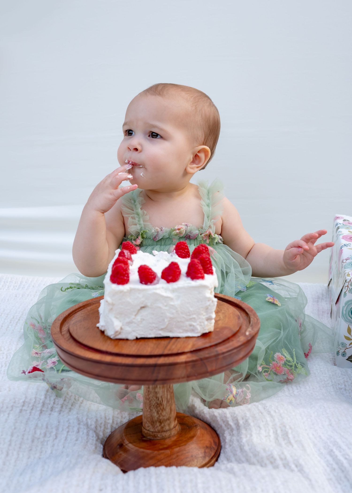 Close up of one year old tasting her smash cake with raspberries on top. Wrightstown NJ Family Photographer