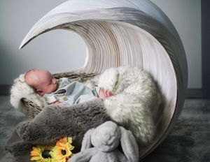 Carousel style montage of newborn baby sleeping in a cozy white swaddle with sunflower accent and soft gray background.