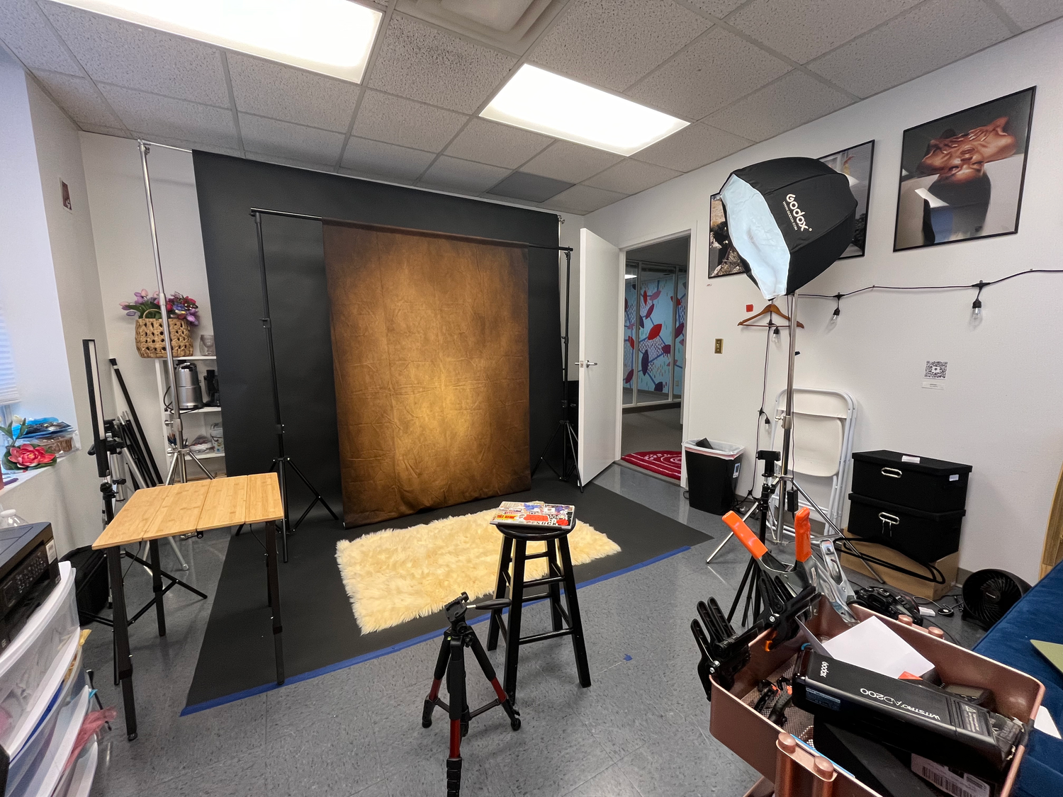 Professional photography studio with backdrop stand, lighting equipment and stools.