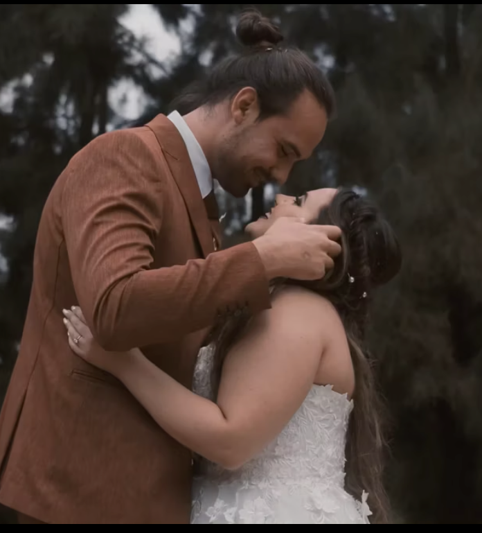 Romantic wedding couple embracing in an intimate moment, with groom wearing a brown suit and bride in white dress.