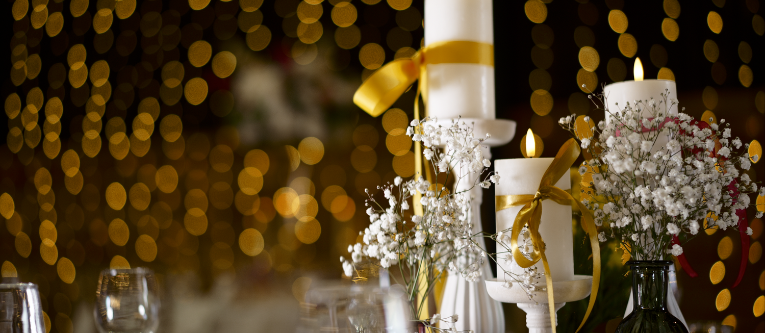 Elegant wedding reception table with candles and bokeh lights in gold tones.