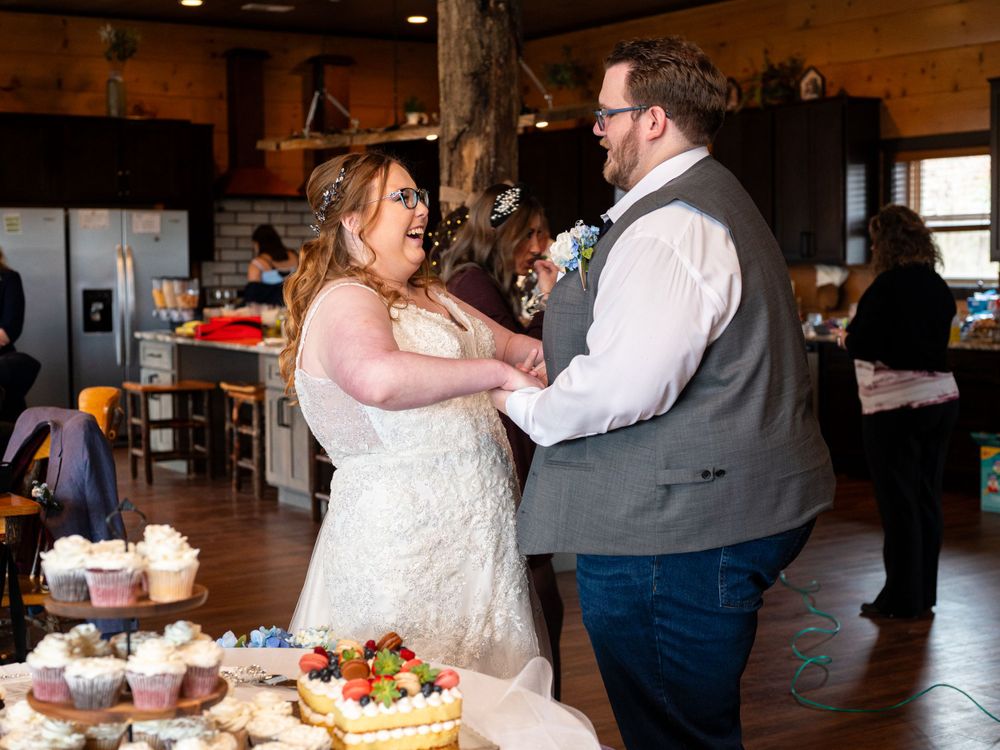 A couple enjoying a celebratory moment together at an indoor rustic venue with desserts on display.
