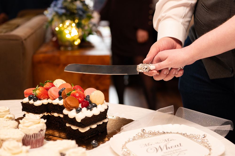 Someone cutting a chocolate cake decorated with fresh berries and whipped cream.