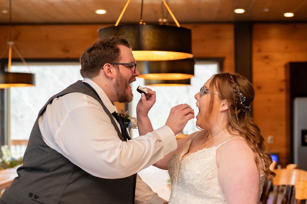 Joyful wedding moment as couple feeds each other cake during reception.