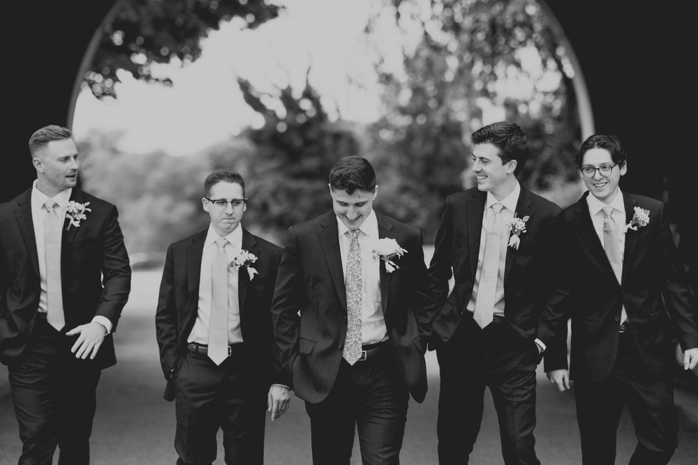 Wedding groomsmen walking in a candid black and white portrait.
