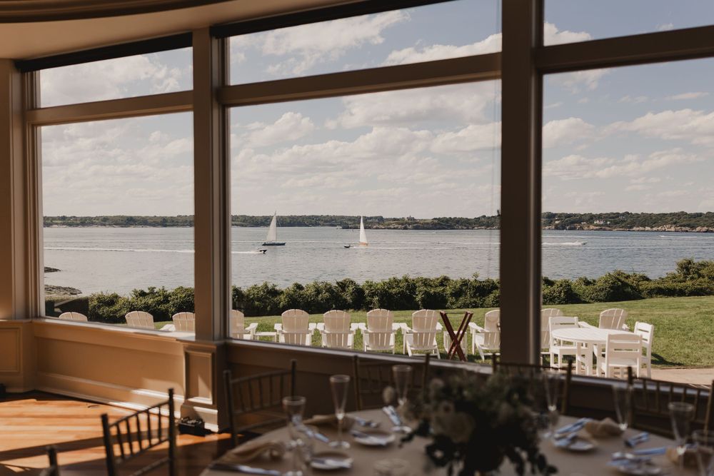Waterfront wedding venue view showing sailboats and table settings through large windows.