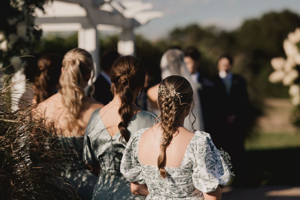 Artistic wedding ceremony shot focusing on bridesmaids' lace details and braided hair.