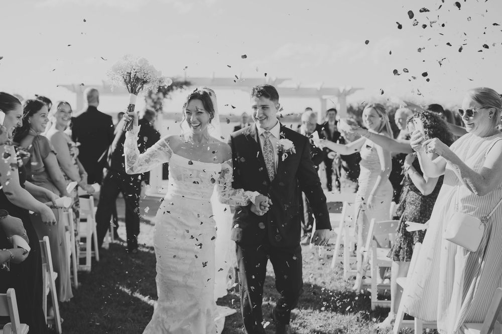 Wedding guests shower the newlyweds with confetti during their outdoor ceremony recessional.