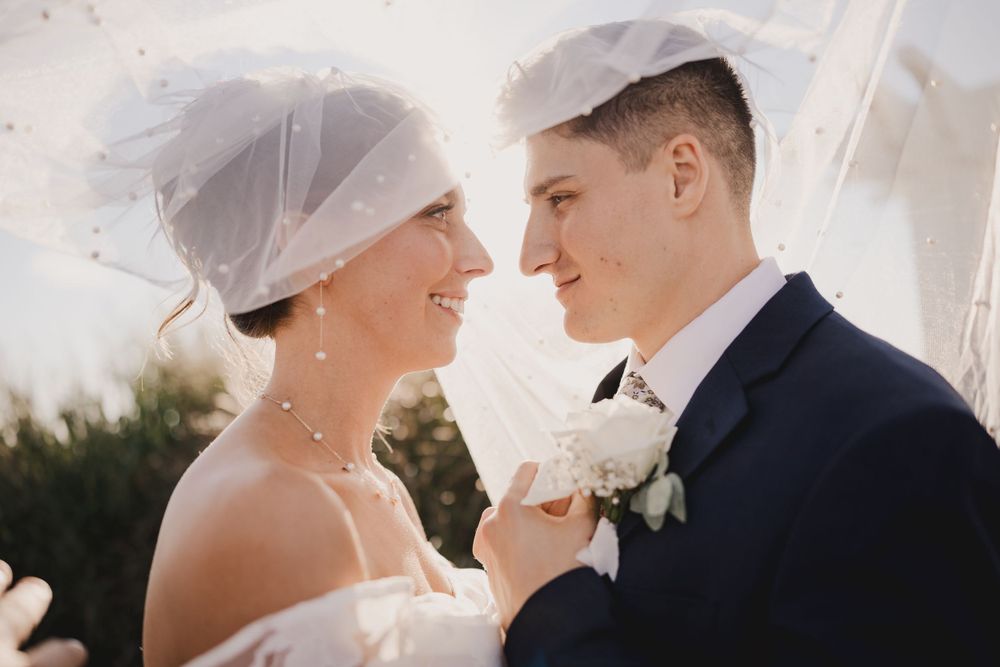 Close-up shot of a tender moment between newlyweds under a wedding arch.